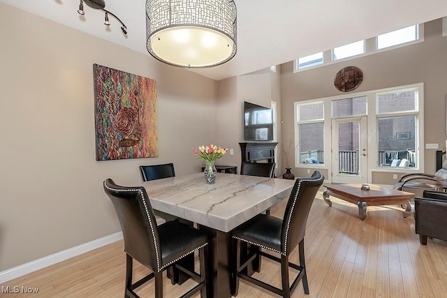 dining room featuring track lighting, light wood-style flooring, and baseboards