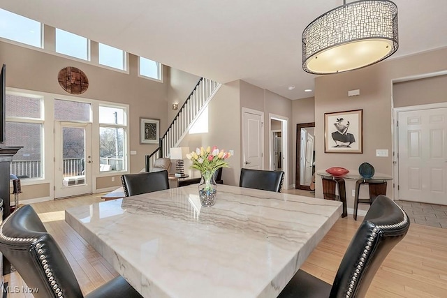 dining space with light wood-type flooring, baseboards, and stairs