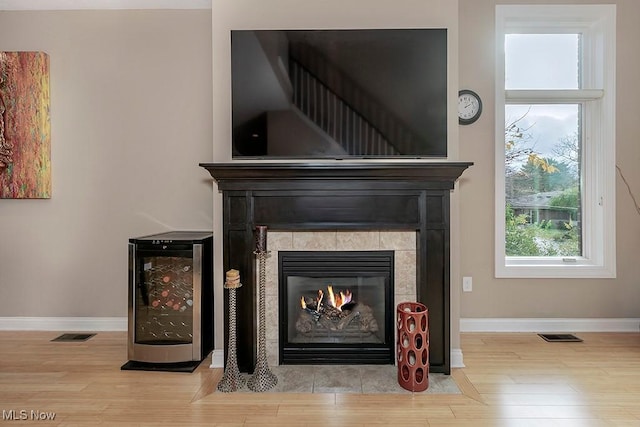 details featuring visible vents, beverage cooler, wood finished floors, baseboards, and a tile fireplace