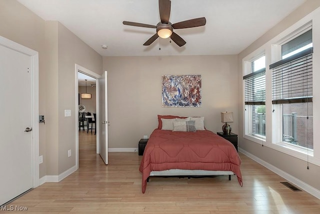 bedroom with visible vents, light wood-style flooring, baseboards, and ceiling fan