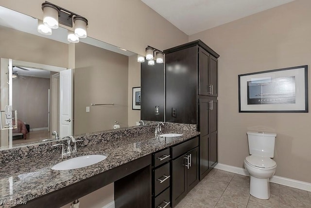 full bath with double vanity, toilet, baseboards, and a sink