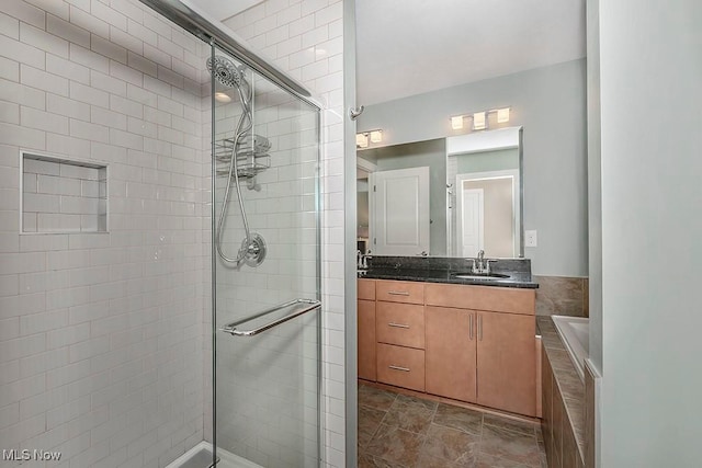 bathroom featuring stone finish flooring, a stall shower, and vanity