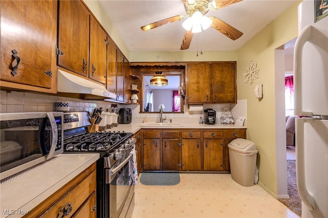 kitchen featuring under cabinet range hood, light countertops, appliances with stainless steel finishes, and a sink