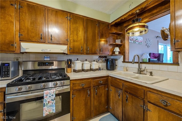 kitchen with under cabinet range hood, appliances with stainless steel finishes, light countertops, and a sink