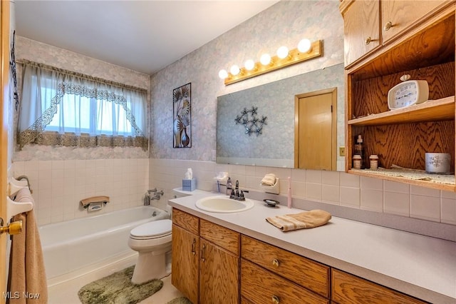 bathroom with a bath, toilet, wallpapered walls, and vanity