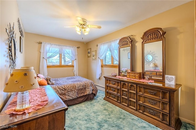 bedroom featuring baseboard heating, multiple windows, a ceiling fan, and carpet