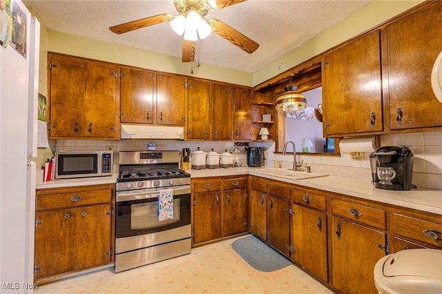 kitchen featuring a sink, under cabinet range hood, appliances with stainless steel finishes, light countertops, and light floors