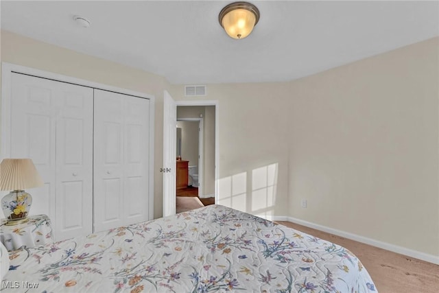 carpeted bedroom featuring a closet, visible vents, and baseboards