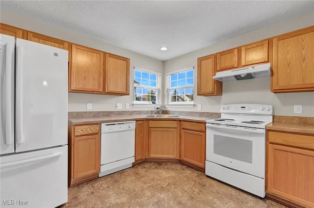 kitchen featuring under cabinet range hood, light countertops, white appliances, a textured ceiling, and a sink