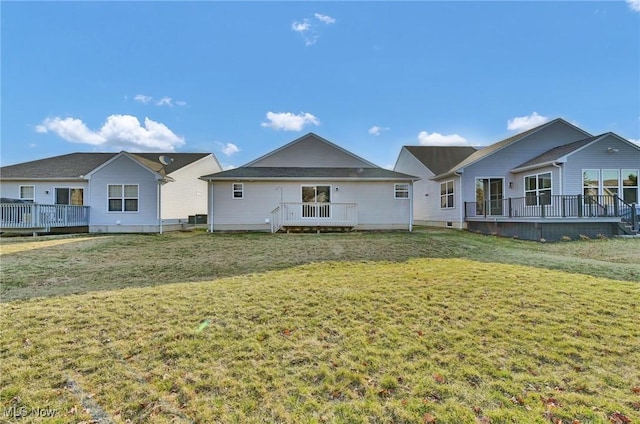 rear view of house featuring a wooden deck and a yard