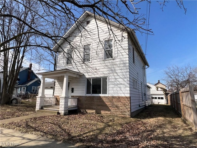 view of front of property with stone siding, a porch, and fence