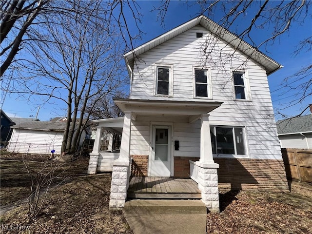 view of front of home featuring brick siding, a porch, and fence