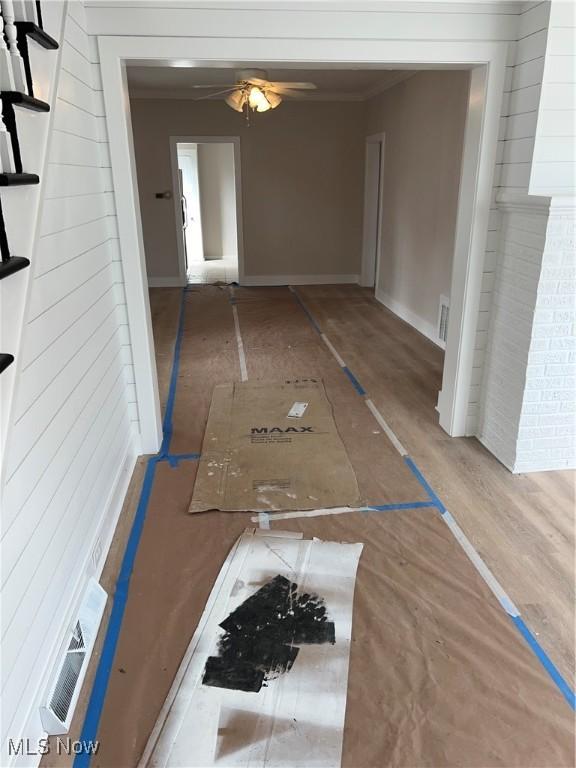 corridor featuring visible vents, baseboards, and wood finished floors