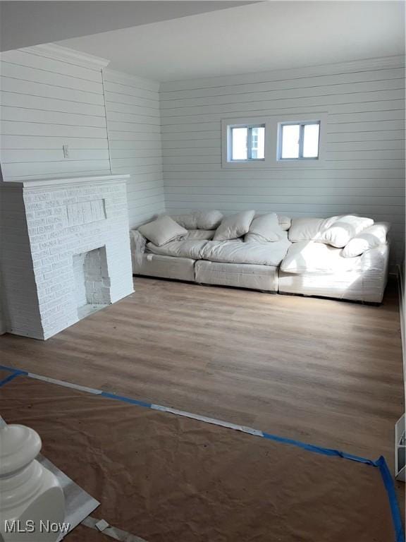 living area with a brick fireplace and wood finished floors