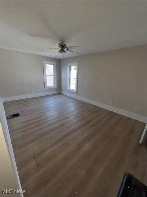 unfurnished room with wood finished floors, baseboards, visible vents, and ceiling fan