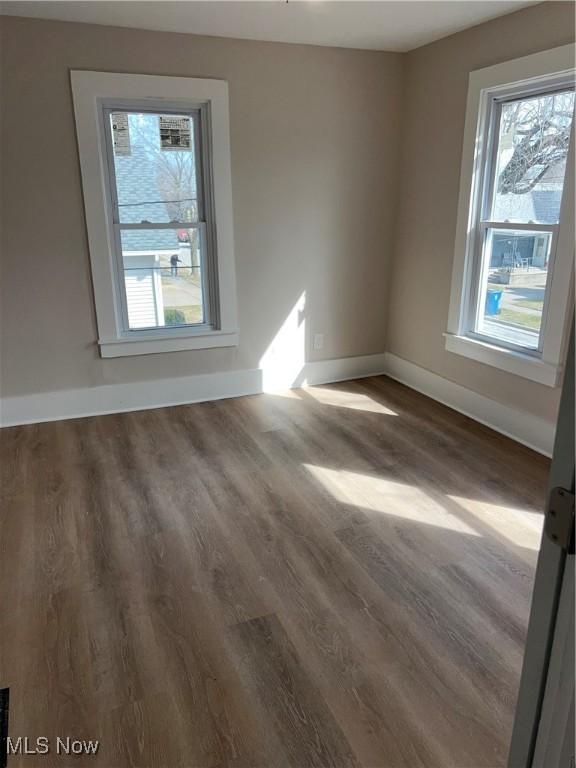 spare room with baseboards and wood finished floors