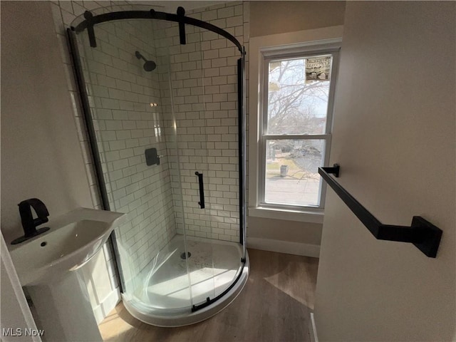 full bathroom with a shower stall, plenty of natural light, wood finished floors, and baseboards