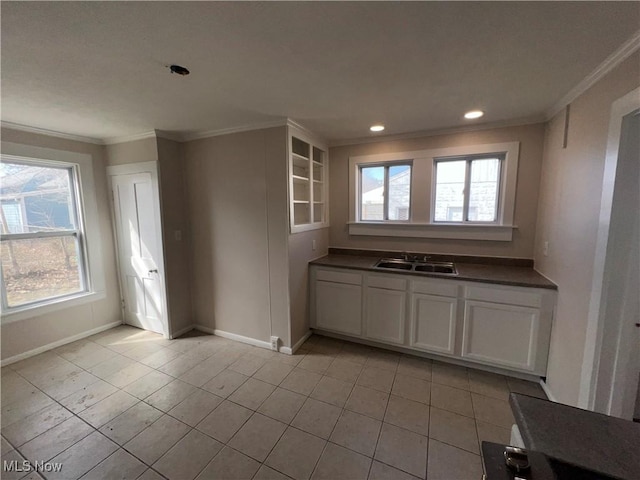 kitchen with a sink, baseboards, dark countertops, and crown molding