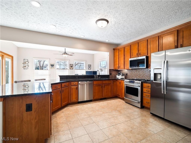 kitchen featuring decorative backsplash, brown cabinets, a peninsula, and stainless steel appliances