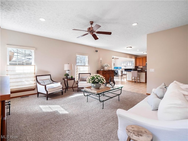 living room with light carpet, plenty of natural light, and a textured ceiling