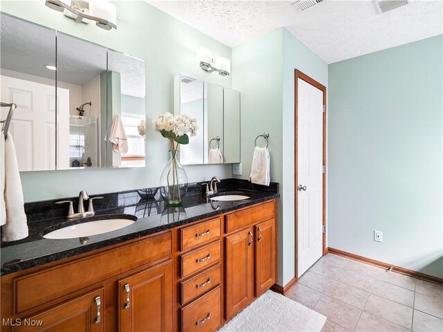 full bathroom with tile patterned floors, a textured ceiling, and a sink