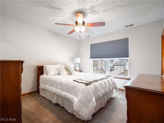 bedroom with carpet flooring, a textured ceiling, baseboards, and visible vents