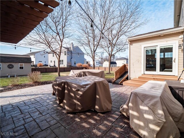 view of patio with area for grilling, fence, and a residential view