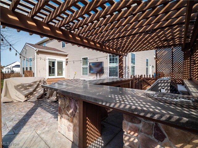 view of patio featuring outdoor dry bar and fence