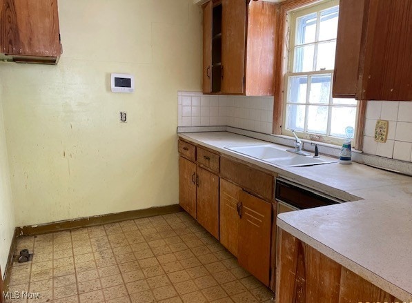 kitchen featuring light floors, baseboards, a sink, light countertops, and backsplash