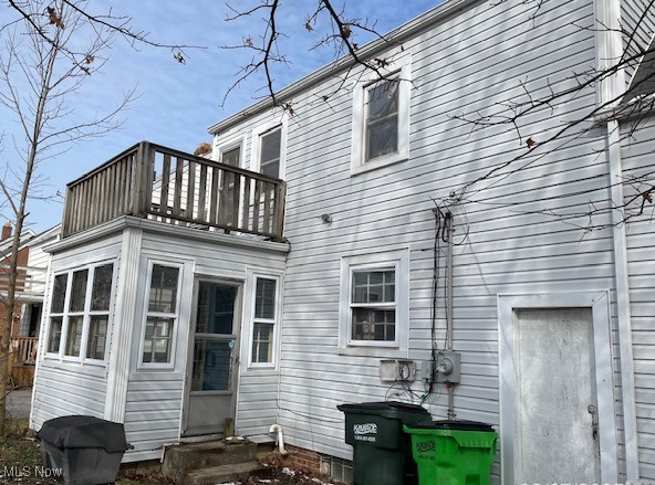 back of property with entry steps and a balcony