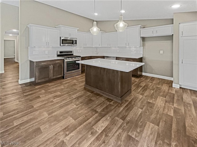 kitchen featuring tasteful backsplash, appliances with stainless steel finishes, arched walkways, and a sink