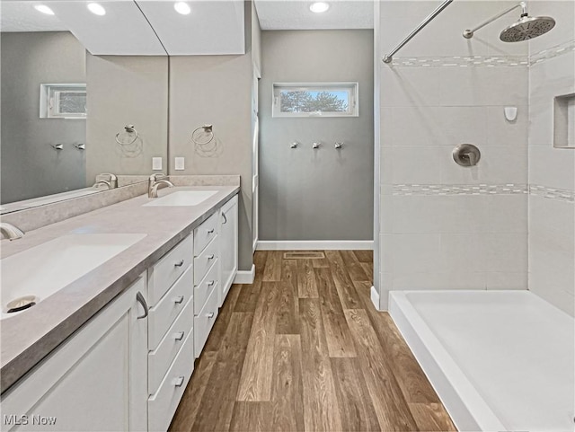 full bathroom featuring tiled shower, wood finished floors, and a sink