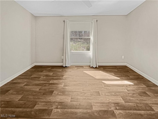 empty room featuring visible vents, baseboards, and wood finished floors