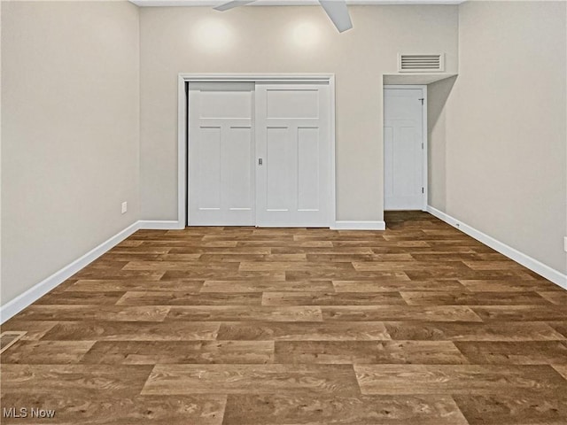 unfurnished bedroom featuring wood finished floors, visible vents, a closet, and baseboards