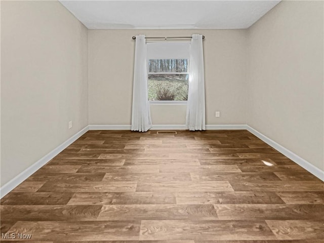 spare room with visible vents, wood finished floors, and baseboards