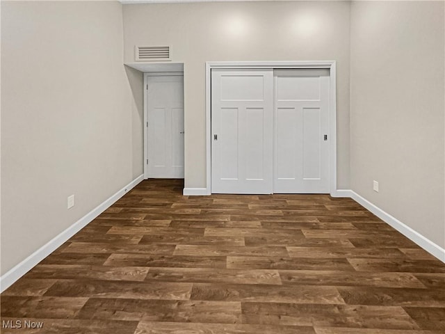 unfurnished bedroom featuring visible vents, baseboards, and dark wood-type flooring