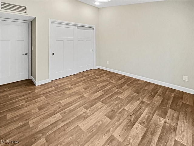 unfurnished bedroom featuring a closet, visible vents, baseboards, and wood finished floors