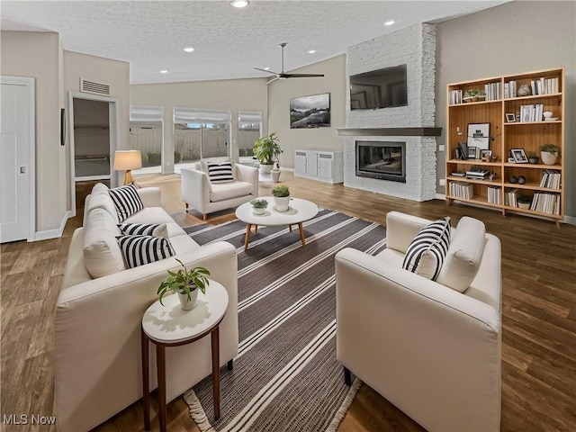 living room featuring a textured ceiling, wood finished floors, visible vents, and ceiling fan