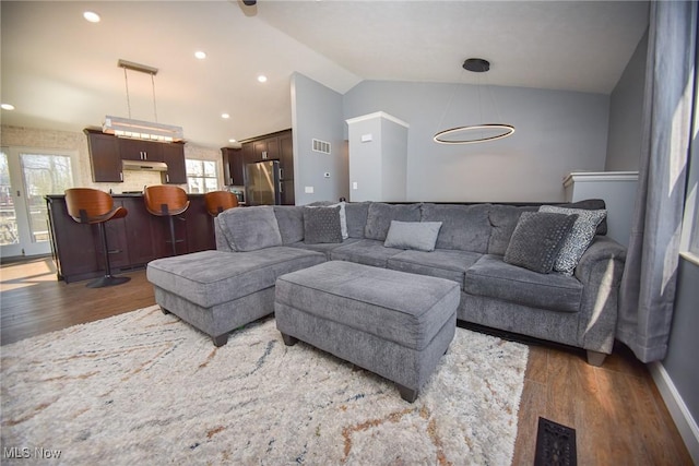 living area with vaulted ceiling, wood finished floors, and visible vents