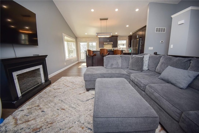 living area featuring visible vents, vaulted ceiling, recessed lighting, a fireplace, and dark wood-style flooring