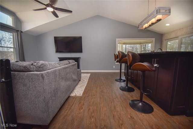 living area featuring dark wood finished floors, lofted ceiling, a ceiling fan, and baseboards