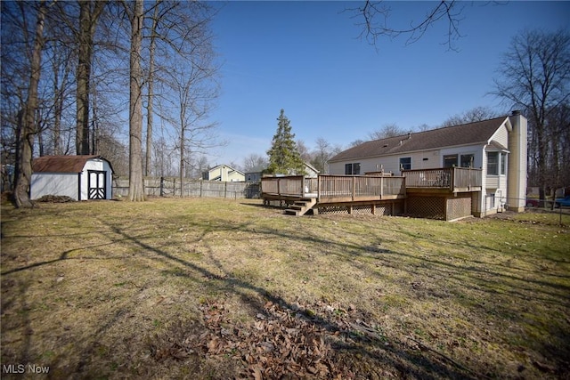 view of yard featuring a shed, an outdoor structure, a deck, and fence