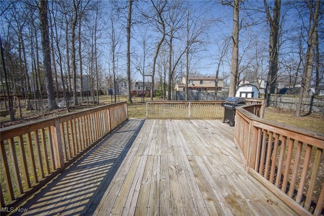 wooden deck with grilling area, a shed, a residential view, a fenced backyard, and an outdoor structure