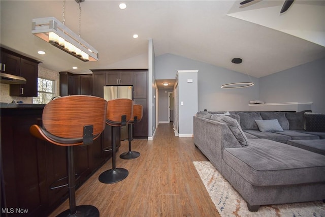 living room featuring recessed lighting, light wood finished floors, baseboards, ceiling fan, and vaulted ceiling