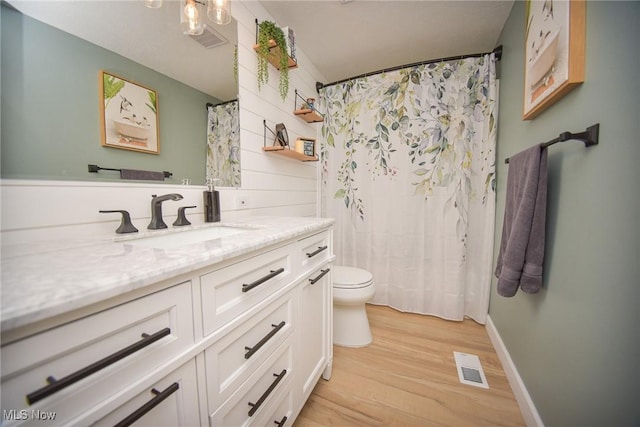 full bath featuring visible vents, toilet, wood finished floors, baseboards, and vanity