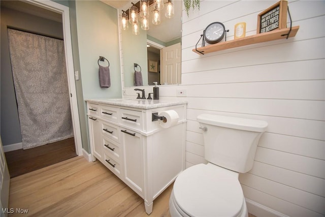 full bathroom with vanity, toilet, wood finished floors, and wood walls