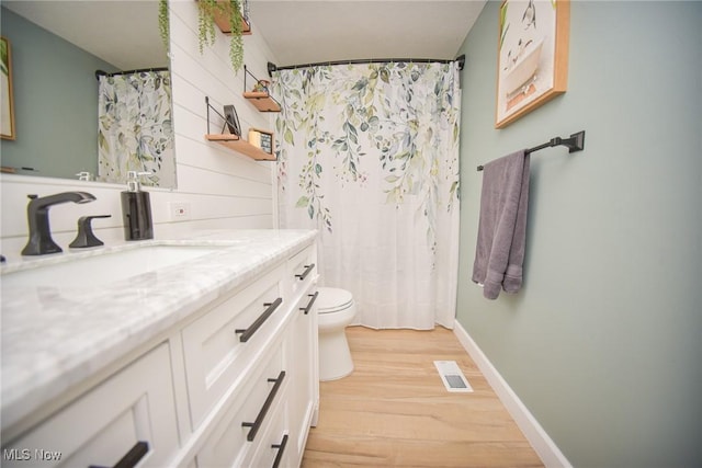 full bathroom with visible vents, baseboards, toilet, wood finished floors, and vanity