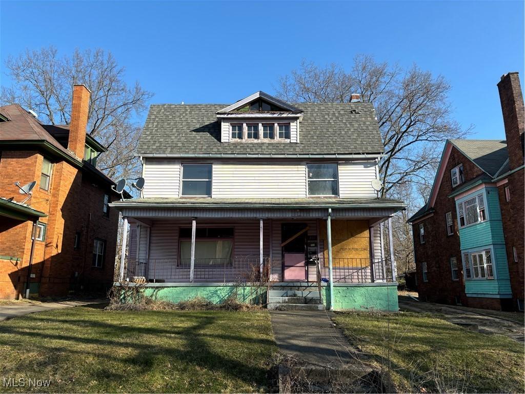 american foursquare style home with a porch, a front lawn, and a shingled roof