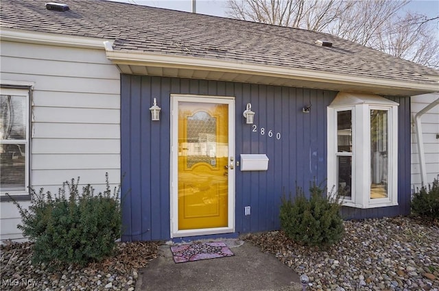 doorway to property with a shingled roof