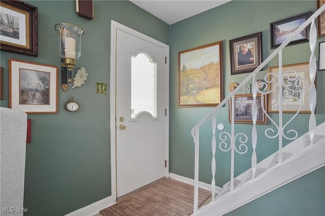 foyer entrance with baseboards, wood finished floors, and stairs